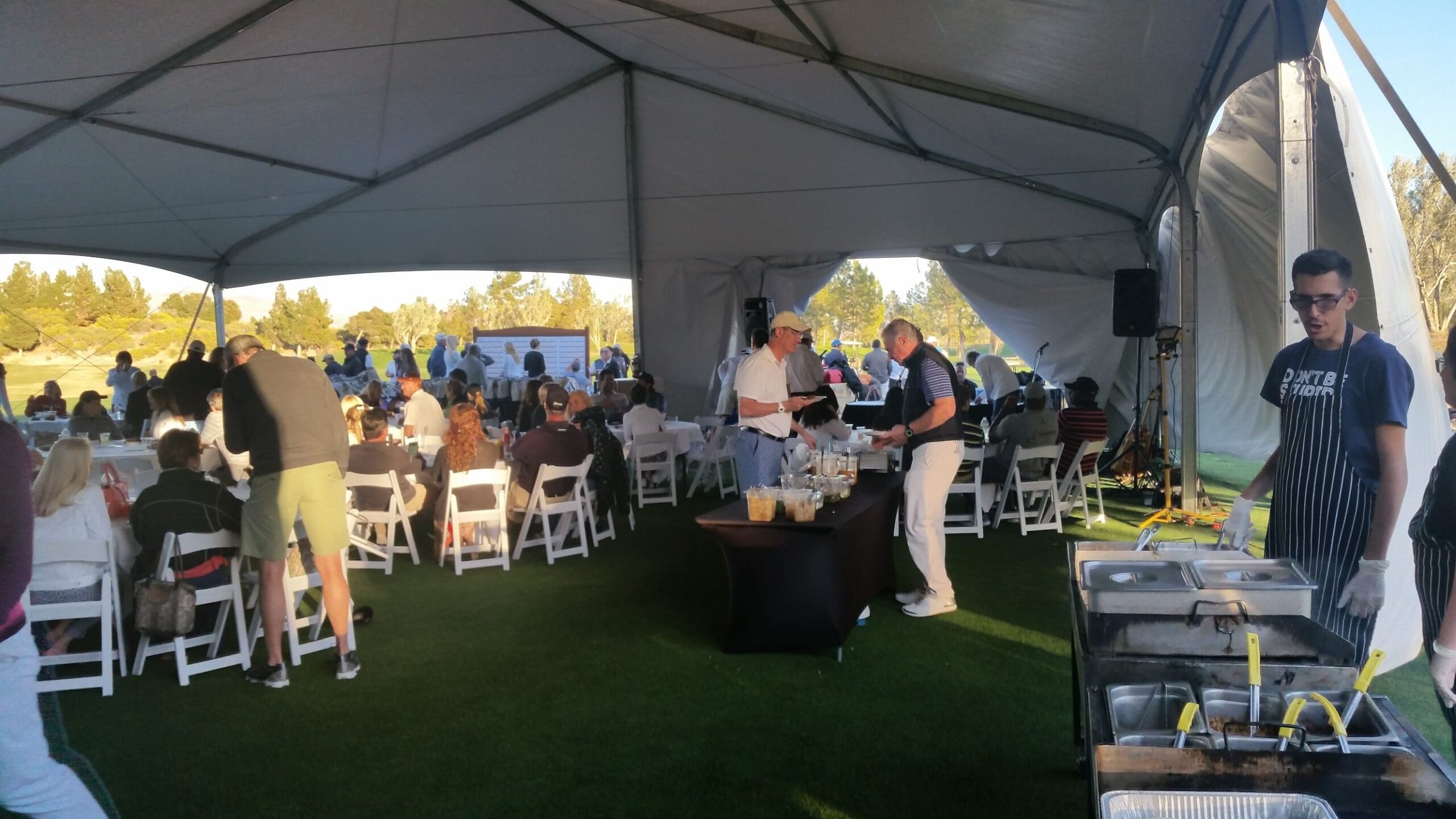 Best Taco Catering , NV - A taco catering event under a large outdoor tent in Las Vegas, NV, featuring attendees seated at tables and a catering team working at a serving station in the foreground.